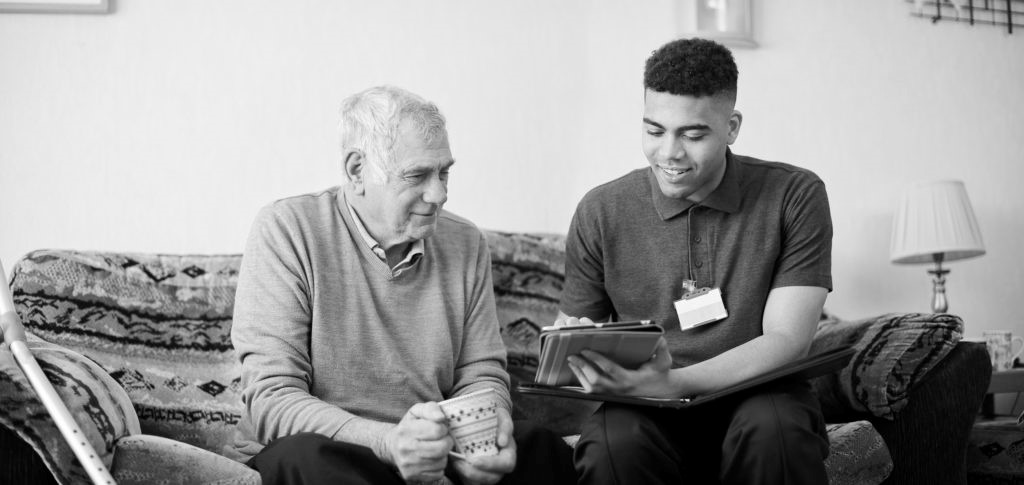 Carer showing an elderly man a tablet